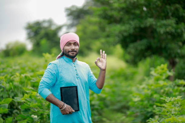 happy young Indian farmer using smart phone , farmer showing tablet, pointing screen