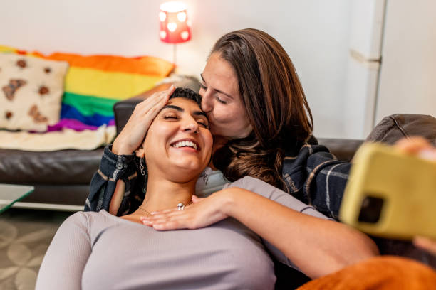 Happy lesbian couple taking a selfie while relaxing on the couch