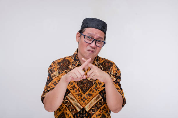 istock A meek middle aged islamic man saying no, gesturing with both index fingers making an x-mark. Against a proposal or law. Isolated on a white background. 2167886479