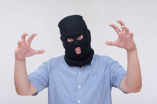 istock A scary and unhinged evil man wearing a black ski mask makes a threatening though comical gesture, showing his claws. Isolated on a white backdrop. 2167886535