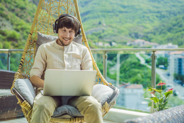 istock Handsome caucasian man sitting on the terrace working from home using computer laptop. Young man teaches a foreign language or learns a foreign language on the Internet on his balcony. Online language school lifestyle 2167886706