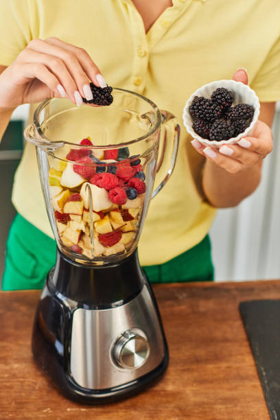 istock Young woman prepares a vibrant fruit smoothie in a sunny kitchen 2167887996