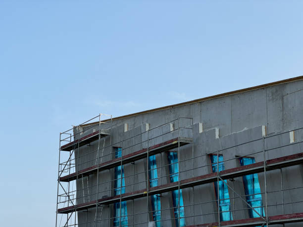istock Scaffolding set up around a large concrete building under construction with blue coverings on the windows 2167888092