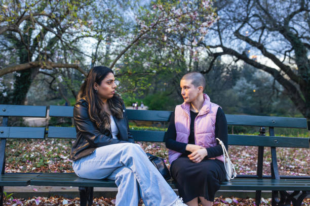 istock Two Women Sharing Quiet Moment on Park Bench at Dusk 2167888899
