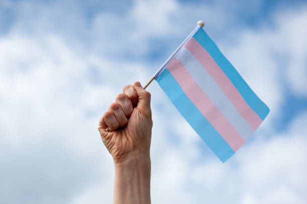 istock Hand holds up transgender pride flag against the sky 2167891282