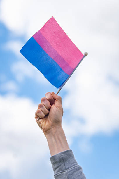istock Hand holds up bisexual pride flag against sky 2167891295