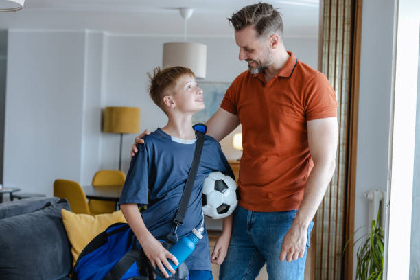 Father embracing his teenage son before sports training stock photo