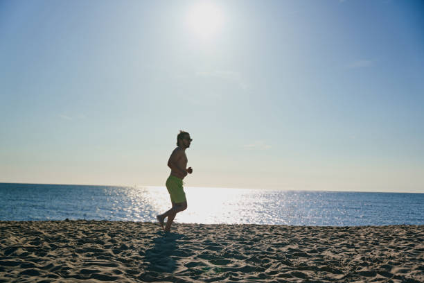 Young overweight man is running on the beach.
