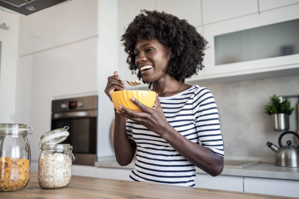 istock A woman is sitting at the kitchen counter eating cornflakes for breakfast 2167897276