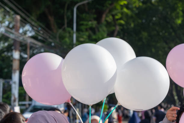people holding strings of white balloons in crowded places