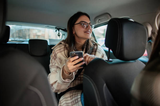 istock Woman riding in a car as a passenger and using her smartphone 2167901287