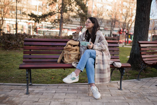 istock Young woman eating lunch on a bench 2167901609