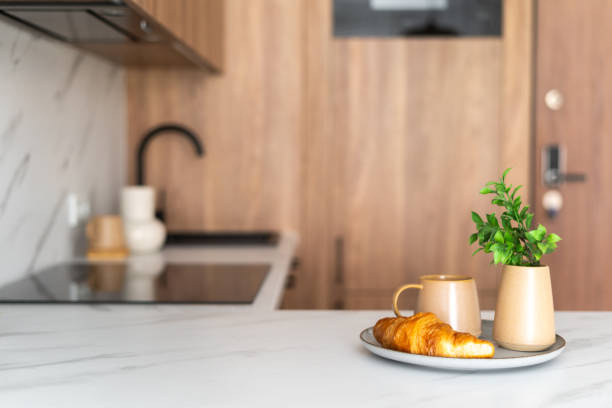 istock A cozy kitchen setting with a croissant, coffee, and a plant on a marble countertop 2167902397