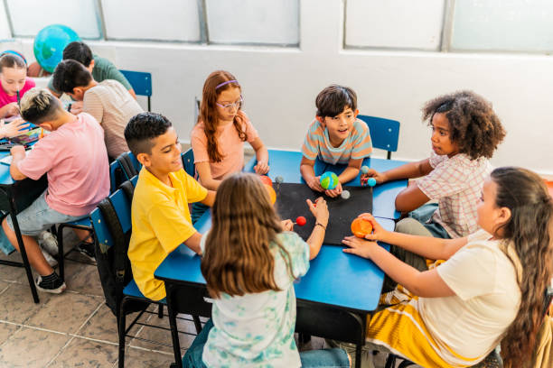 Child students talking and doing a model of solar system during class at school