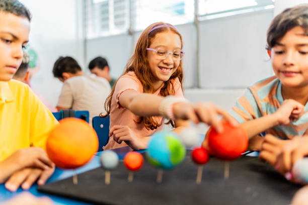 Child students talking and doing a model of solar system during class at school