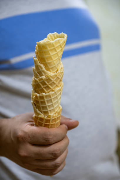 istock A hand holding an ice cream cone on a sunny day, symbolizing summer refreshment and simple pleasure. The delicious, cold treat and blue shirt background emphasize casual enjoyment and indulgence. 2167904146
