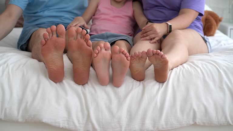 Three barefoot people, mother, father and daughter resting on the sofa, foot closeup, corns and calluses on feet, dry skin on legs, cracked heels