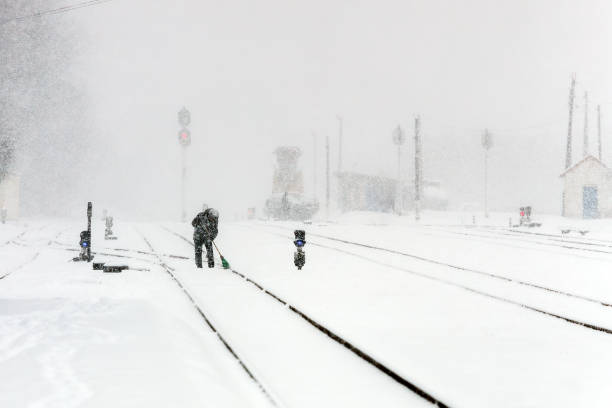 istock Snow covered railway in winter time. Snow covered railway tracks during a blizzard. A man cleans a railway track with a broom. 2167916728