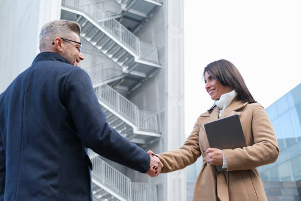 istock Two professionals in suits shake hands outside a modern office building, symbolizing teamwork and successful collaboration in business 2167917135