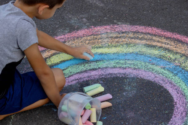 istock the boy draws with chalk on the asphalt. Selective focus 2167920056