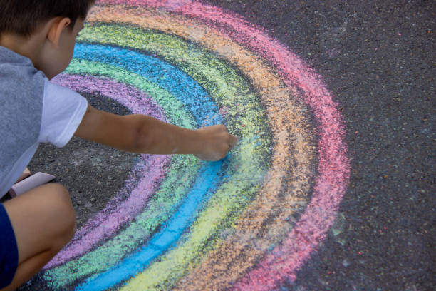 istock the boy draws with chalk on the asphalt. Selective focus 2167920060