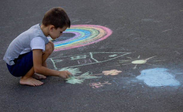 istock the boy draws with chalk on the asphalt. Selective focus 2167920062