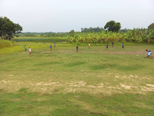Faridpur, Bangladesh - March, 04, 2024: Local young boys playing football in the late afternoon at local playing ground in Madhukhali, Faridpur, Bangladesh.