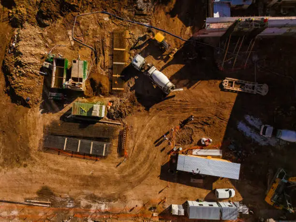 Top aerial view of a construction site with cement mixer truck, machinery and workers Top aerial view of a construction site with cement mixer truck, machinery and workers