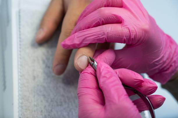 istock Manicurist cuts off cuticle to male client using nippers. 2167923933
