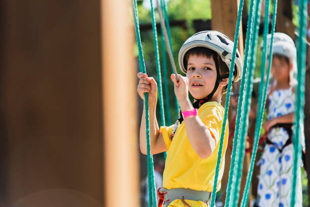 A boy is rock climbing in a rope park, walking along a cable car and overcoming obstacles