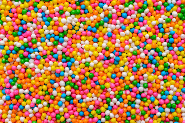 Colorful sugar sprinkle dots for decorating children's treats forming a blurred background.