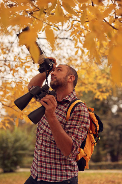 istock Man using binoculars and camera for bird and animal watching in nature. 2167928030
