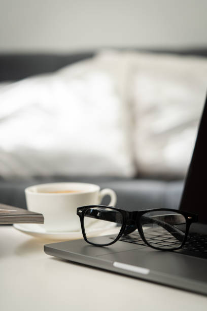 Modern Workspace With Laptop, Glasses, and Magazines close up