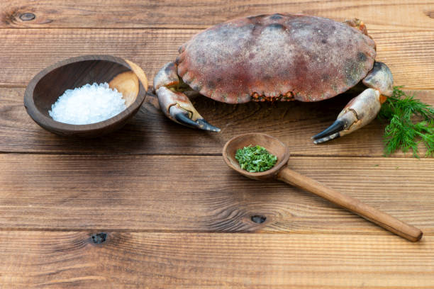 This image shows a crab submerged in water. The crab's body is brown with some dotted textures. Its legs and claws appear very strong, extending outward. The reflections in the water highlight the crab's details, while the blue background and the rippling water effect further enhance the visual appeal of the image