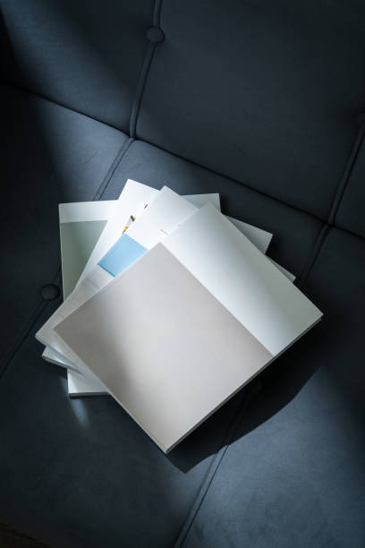 Stack of Magazines on a Black Leather Couch in Soft Light close up