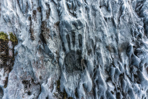 Aged of caveman palm hand print on limestone wall in ice cave on winter