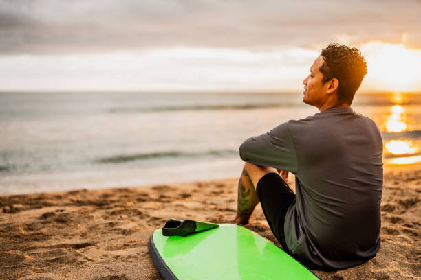 Mid adult surfer man contemplating while looking away on the beach