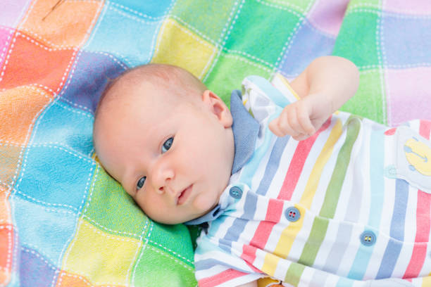 Adorable baby in on colorful blanket. Newborn child relaxing in sunny garden. Picnic with young children. Textile and bedding for kids. Family morning at home.