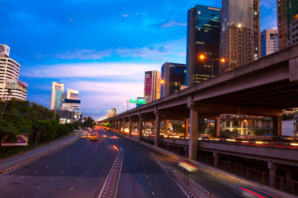Night traffic scene in Bangkok Chatuchak near Mochit with main road  Vivhadi Rangsit Rd and Don Muang Toll Way. Long exposure of cityscape and traffic. Modern office building skyline opposite to Mochit BTS station which is behind skyline at right side out of frame