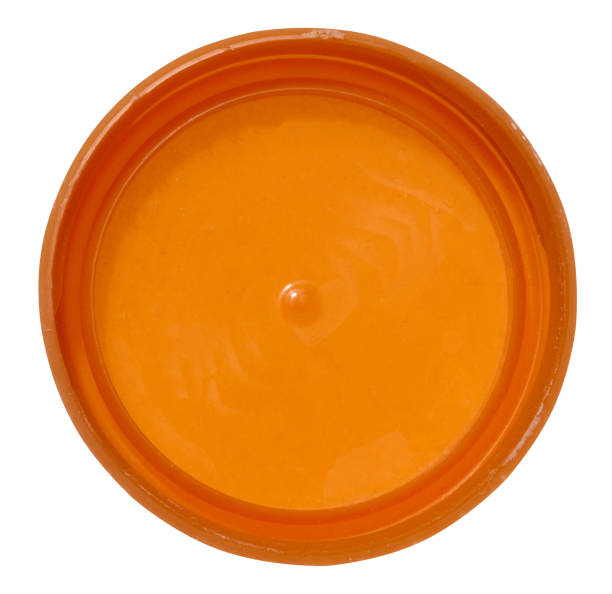 Orange plastic bottle cap on isolated background, top view