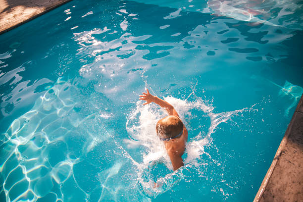 Active preschool boy jumping and playing in the swimming pool. above view, copy space