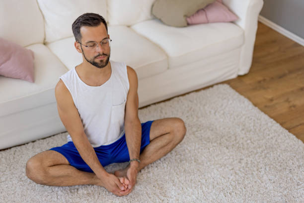 istock Person meditating cross-legged on a white carpet. 2167955553