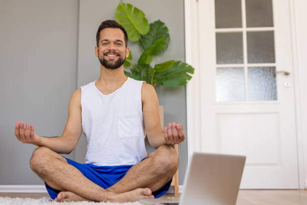 istock Man meditating on a rug in a living room using a laptop 2167955654