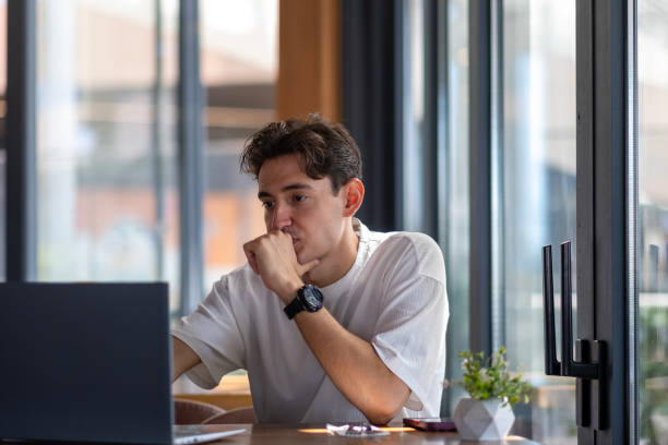 istock Young man working with laptop in cafe looks thoughtful 2167957268