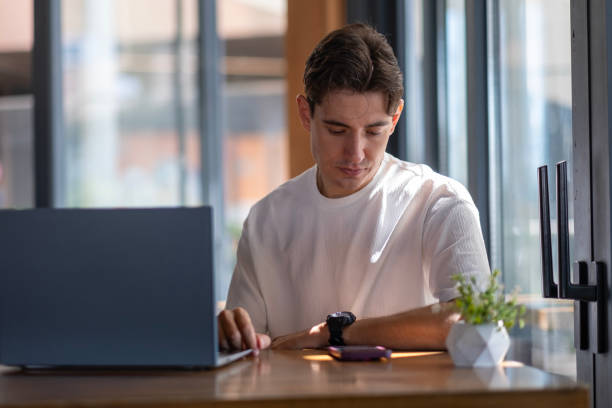 istock Young man checking his watch while working in cafe 2167957275