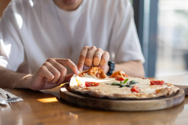 istock Young man's hand taking slice of pizza in restaurant 2167957332
