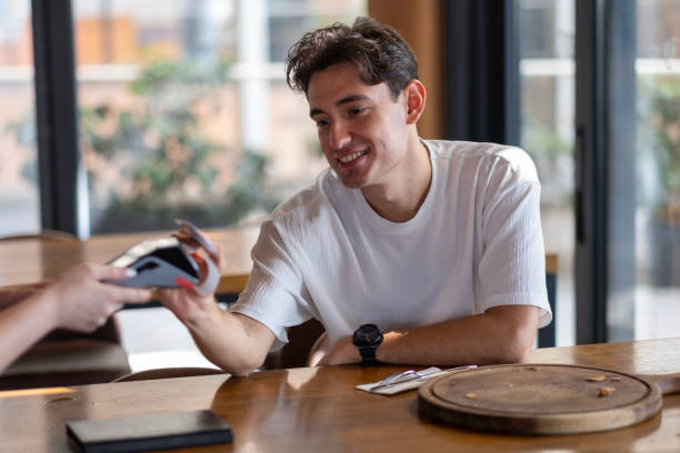 istock Young man making contactless payment with credit card in restaurant 2167957367