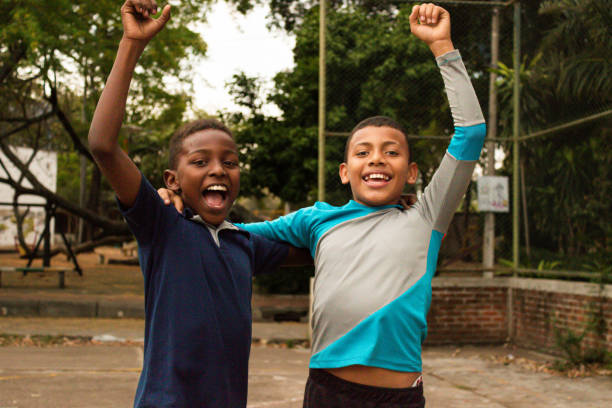 Black Latino children with their arms up celebrating a goal on a park field in Neiva - Huila - Colombia