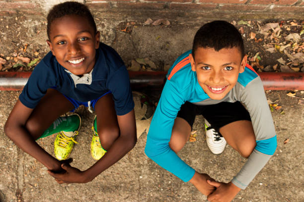 Two happy black Latino children sitting on the ground and looking at the camera in a park in Neiva - Huila - Colombia