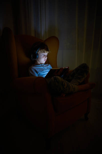 istock Boy in headphones playing on tablet in darkness 2167959720